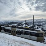 Modern Rigi train climbing through snow-covered Swiss Alps with breathtaking winter mountain views