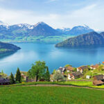 Panoramic view of Vitznau village and Lake Lucerne with alpine mountains in the background on a sunny spring day